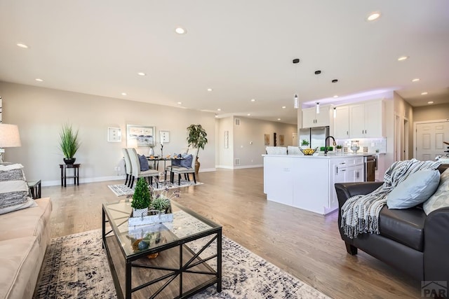 living area with light wood finished floors, baseboards, and recessed lighting