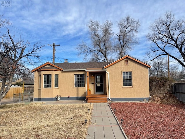 view of front of home with a shingled roof, fence, and stucco siding