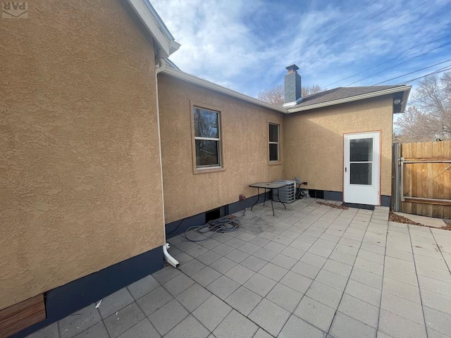 exterior space with a chimney, a patio area, fence, and stucco siding