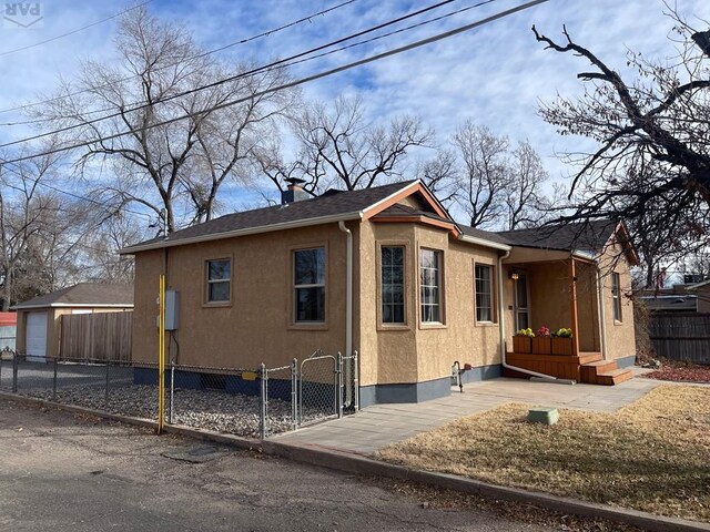 view of home's exterior with a shingled roof, a chimney, fence, and stucco siding