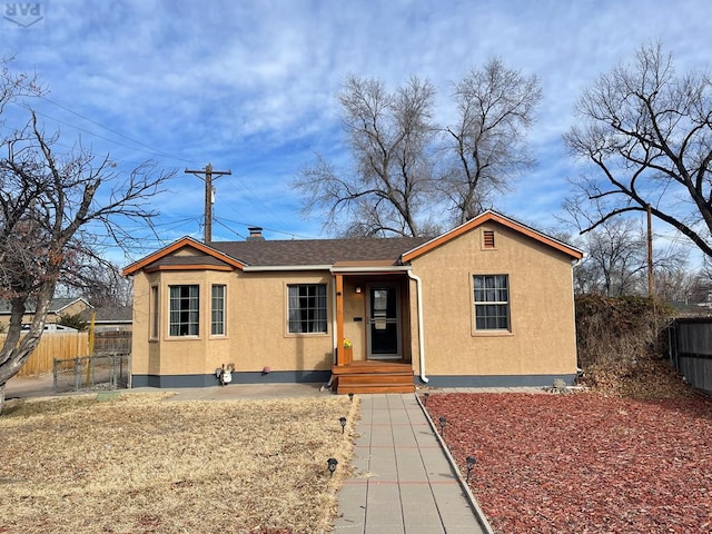 view of front facade with a shingled roof, fence, and stucco siding