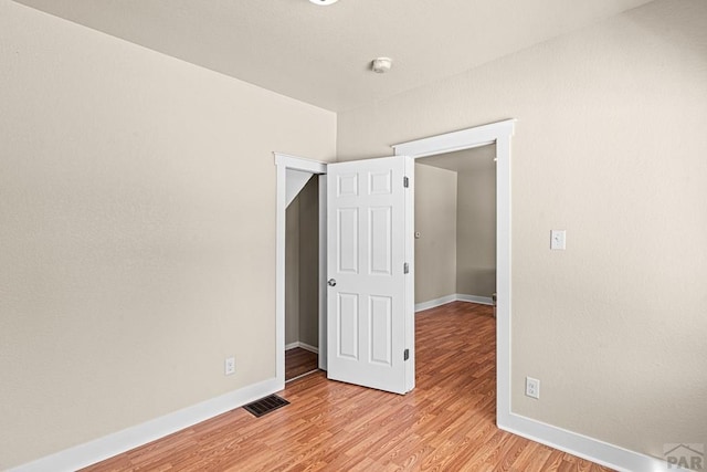 spare room featuring baseboards, visible vents, and light wood finished floors