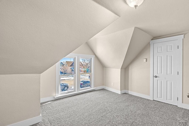 bonus room featuring carpet, baseboards, and a textured ceiling