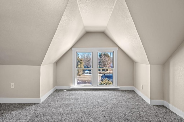 bonus room featuring carpet, baseboards, and a textured ceiling