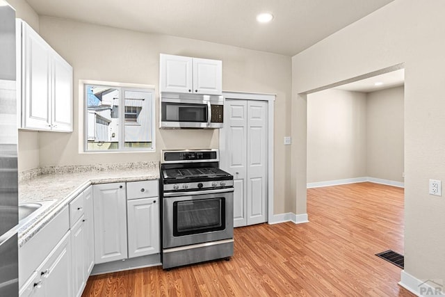 kitchen featuring stainless steel appliances, visible vents, light wood-style floors, white cabinets, and baseboards