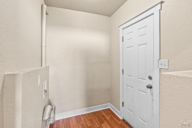 entryway featuring a textured ceiling, baseboards, wood finished floors, and a textured wall