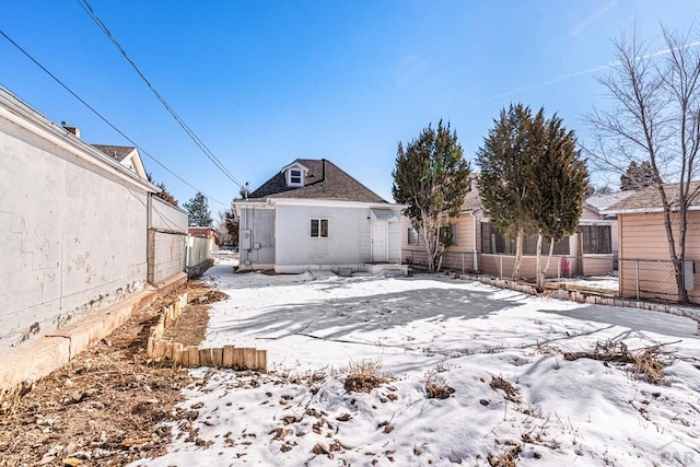 snow covered back of property featuring fence