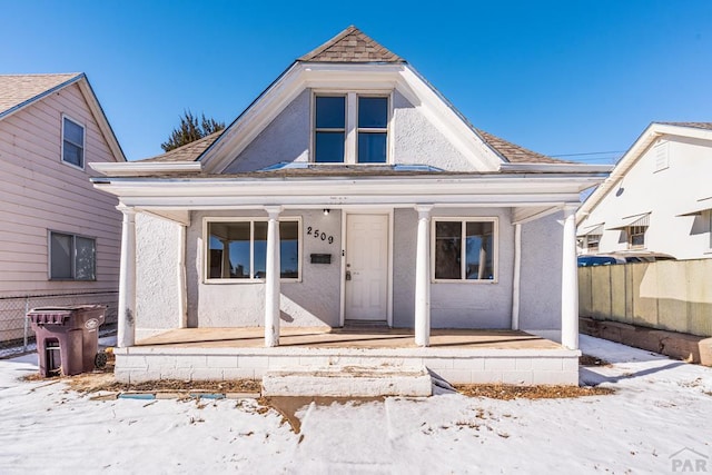 view of front of house featuring a porch, roof with shingles, and fence