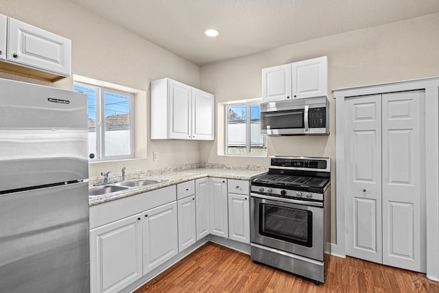 kitchen featuring light countertops, appliances with stainless steel finishes, a sink, and white cabinets