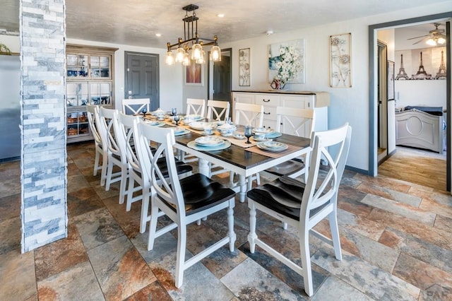 dining space with ceiling fan, washer / dryer, stone tile flooring, and baseboards
