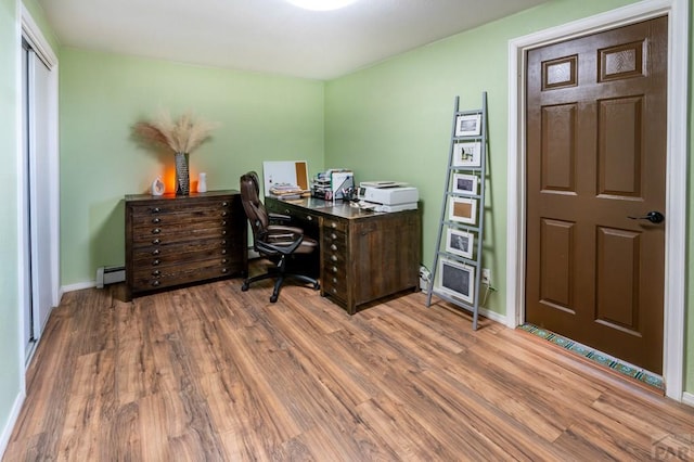office area with a baseboard radiator, wood finished floors, and baseboards