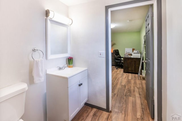 bathroom featuring wood finished floors, toilet, and vanity