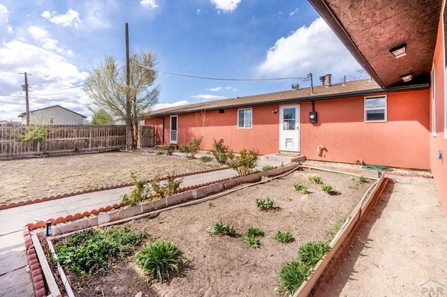 exterior space with a garden, stucco siding, and fence