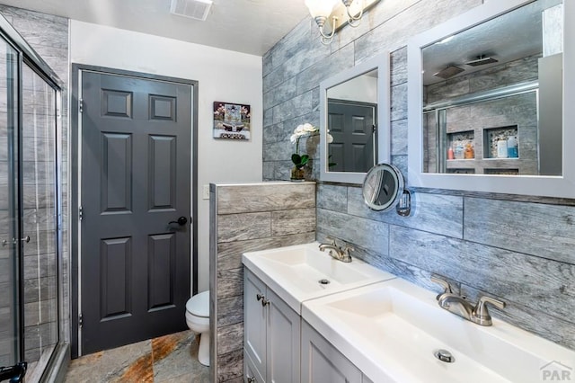 bathroom with a shower stall, tile walls, visible vents, and a sink