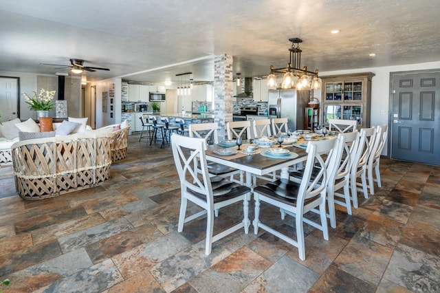 dining room featuring a ceiling fan and stone tile flooring