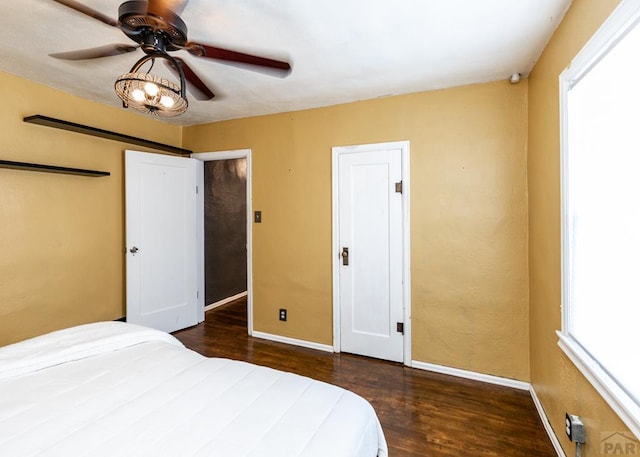 bedroom featuring a ceiling fan, baseboards, and dark wood-type flooring