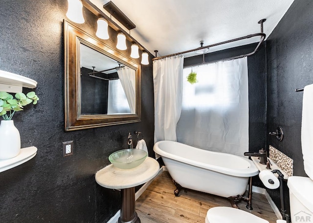 full bath with a wealth of natural light, toilet, and wood finished floors