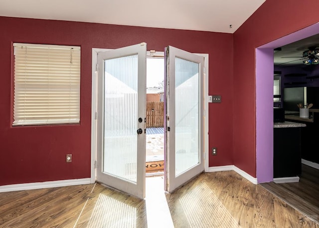 doorway with ceiling fan, baseboards, and wood finished floors