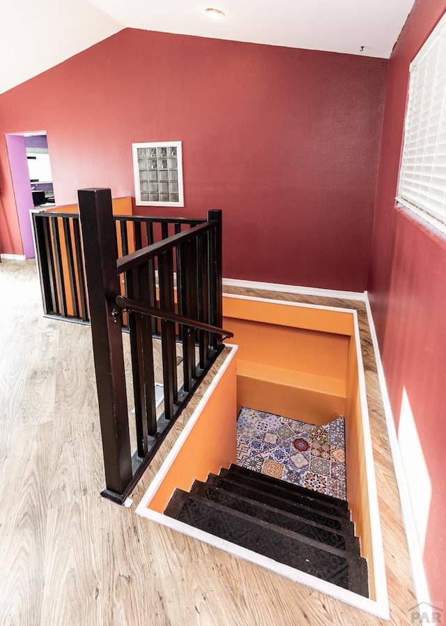 staircase featuring vaulted ceiling, baseboards, and wood finished floors