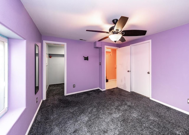 unfurnished bedroom featuring ceiling fan, dark carpet, visible vents, and baseboards