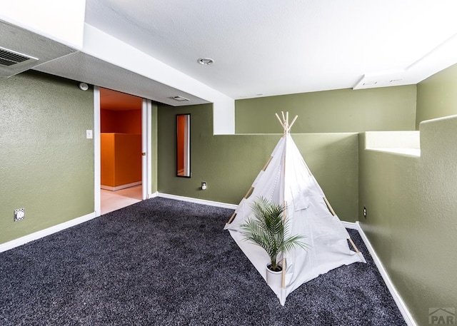 recreation room featuring carpet, visible vents, baseboards, and a textured wall