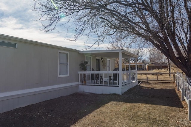 view of home's exterior with covered porch and fence