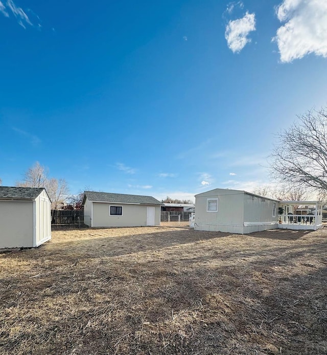 rear view of property featuring a shed, fence, and an outbuilding