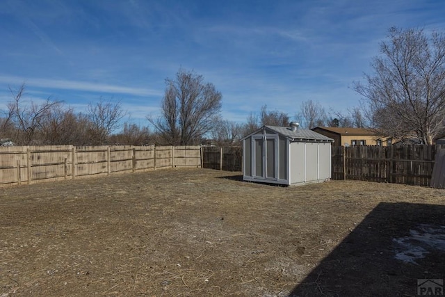 view of yard featuring an outbuilding, a fenced backyard, and a storage unit