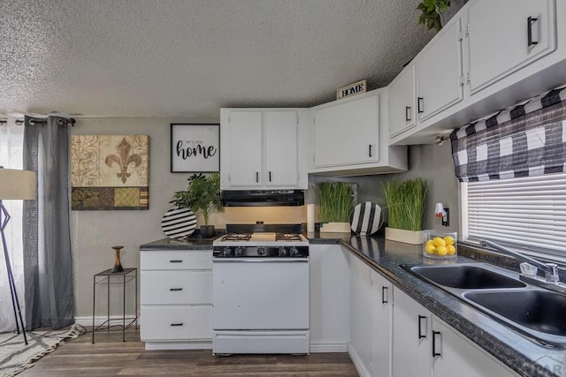 kitchen featuring under cabinet range hood, white cabinets, a sink, and white gas stove