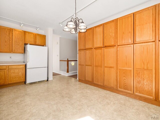3933 Elk Ln, Pueblo, CO 81005 - kitchen featuring light floors, brown cabinets, a chandelier, and freestanding refrigerator