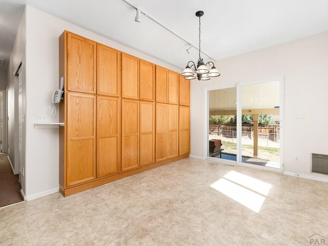 3933 Elk Ln, Pueblo, CO 81005 - unfurnished dining area with a chandelier, track lighting, and baseboards