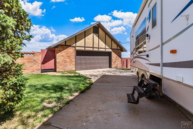 1194 39th Ln, Pueblo, CO 81006 - view of side of home featuring brick siding, a garage, fence, and a yard