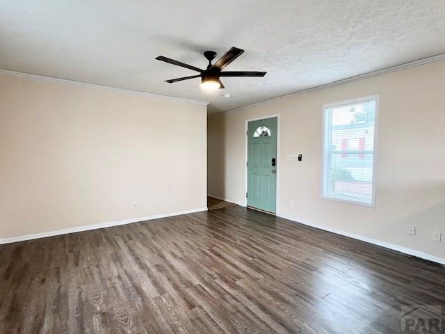 unfurnished room featuring baseboards, ornamental molding, a textured ceiling, a ceiling fan, and dark wood-style flooring