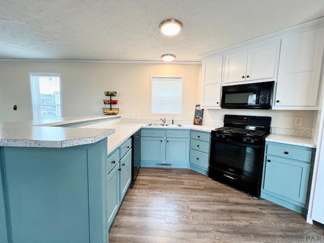 kitchen with blue cabinetry, a textured ceiling, black appliances, and a peninsula