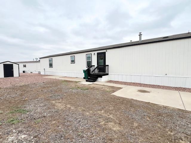 back of house featuring a storage shed and an outbuilding