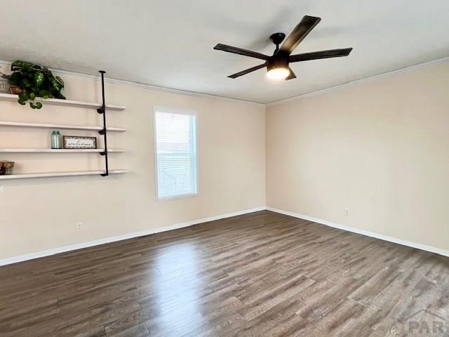 spare room featuring baseboards, wood finished floors, and ornamental molding