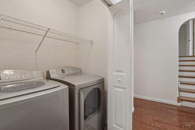 502 S Putter Dr, Pueblo West, CO 81007 - washroom featuring washing machine and dryer, arched walkways, wood finished floors, and baseboards