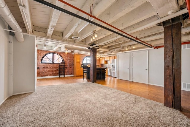201 Lamkin Unit 205, Pueblo, CO 81003 - below grade area with stainless steel fridge, light colored carpet, brick wall, and light wood-type flooring