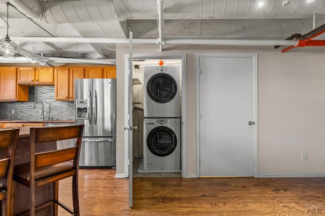 201 Lamkin Unit 205, Pueblo, CO 81003 - kitchen featuring stainless steel refrigerator with ice dispenser, stacked washer / dryer, wood finished floors, and decorative backsplash