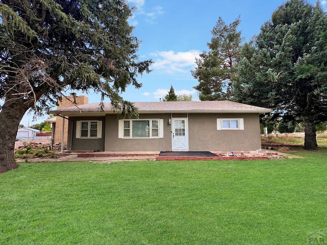 single story home featuring a front yard, a chimney, and stucco siding