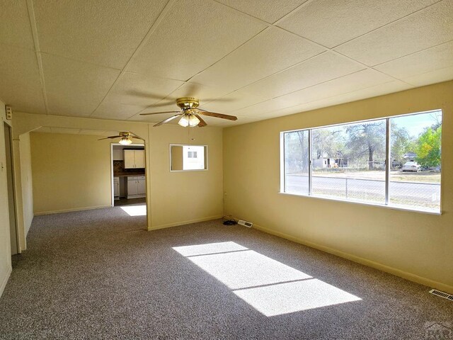 unfurnished room featuring carpet flooring, ceiling fan, visible vents, and baseboards