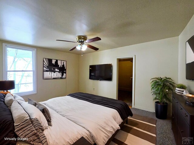 bedroom featuring a textured ceiling, dark colored carpet, a ceiling fan, and baseboards