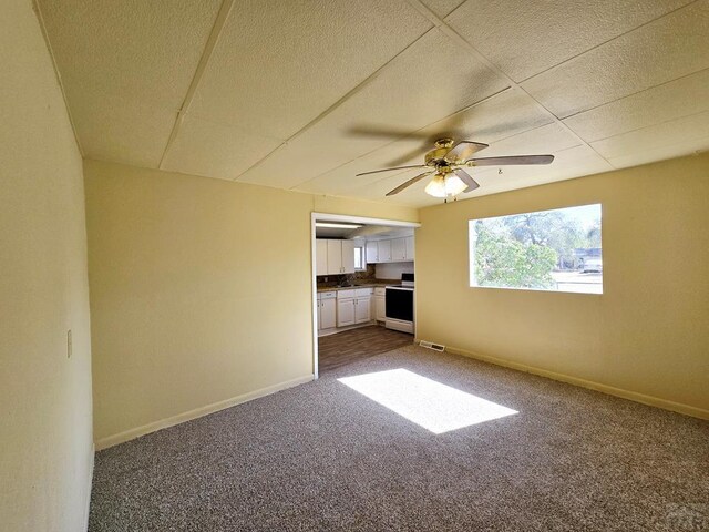 unfurnished room with carpet floors, visible vents, baseboards, and a ceiling fan