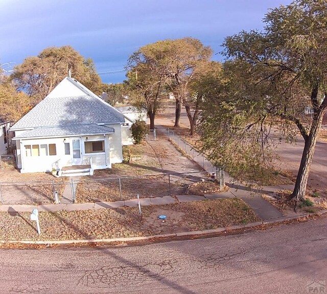 view of front of home with a fenced front yard and a shingled roof