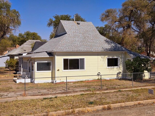 view of home's exterior with a fenced front yard and a shingled roof