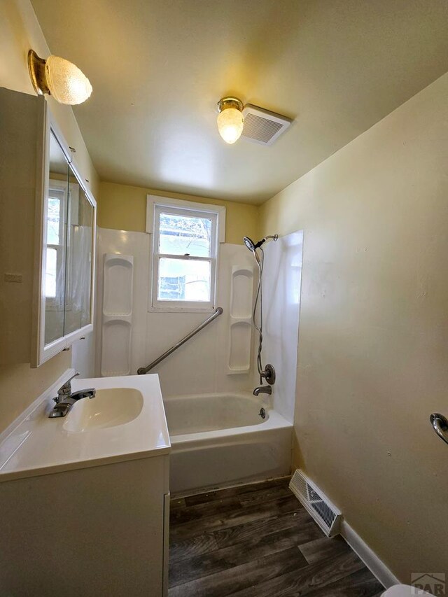 bathroom featuring baseboards, visible vents, wood finished floors,  shower combination, and vanity