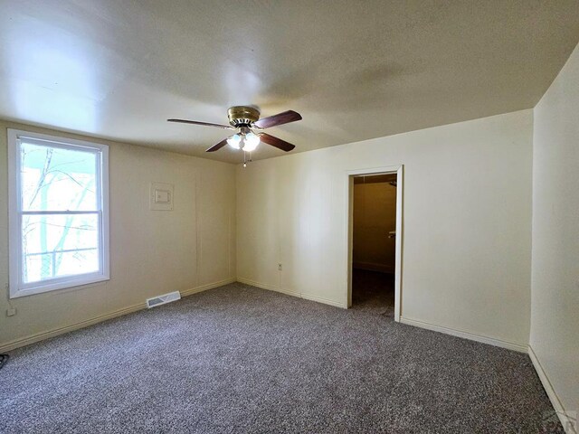 spare room featuring visible vents, dark carpet, a textured ceiling, and baseboards