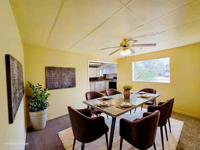 dining area with baseboards, ceiling fan, and light colored carpet