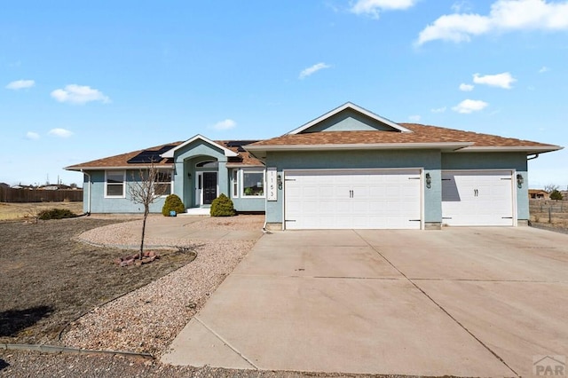 1153 E Kirkwood Dr, Pueblo, CO 81007 - ranch-style home with stucco siding, concrete driveway, roof mounted solar panels, and a garage
