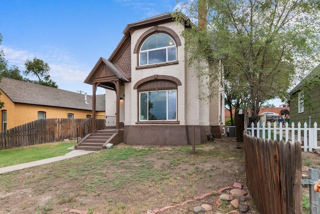 view of front of property featuring a fenced front yard, central AC unit, and brick siding